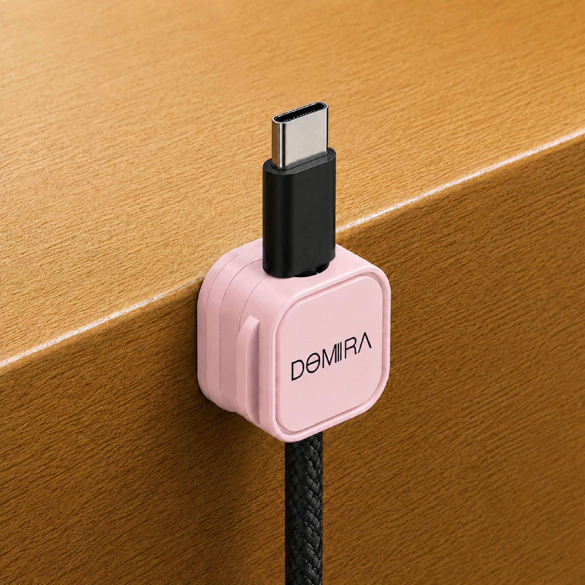 Pink magnetic cable clip mounted on the
edge of a desk holding a charging cable
for easy access and cable organisation.