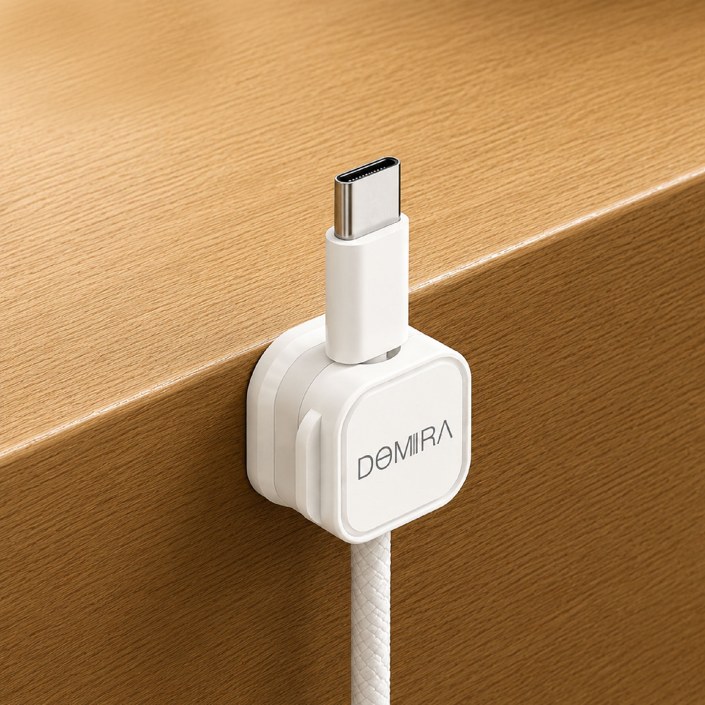 White magnetic cable clip mounted on
the edge of a desk holding a charging
cable for easy access and cable
organisation.