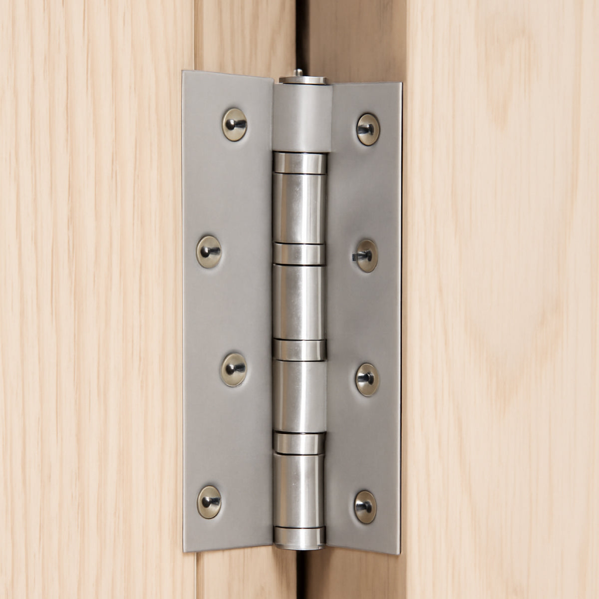 Silver 4 inch door hinges installed on a wooden door